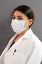 Latina female doctor wearing a clinical gown and masks for protection from covid-19