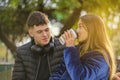 Latina girl drinks coffee in a disposable cup next to a Caucasian boy on the bench in a public park Royalty Free Stock Photo