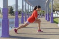 Latina girl with a red t-shirt stretching in a public park Royalty Free Stock Photo