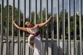 Latina and Hispanic girl, young and pretty, wearing a T-shirt made with a handkerchief and white pants, holding on to a fence with Royalty Free Stock Photo