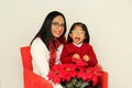 Latina mom and daughter with glasses hat and Christmas garland show their enthusiasm and happiness for the arrival of December and
