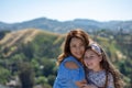 Latina Mother and Daughter Smiling and laughing on a hill in front of yellow flowers