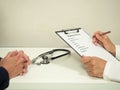 Physician and Patient`s Hands with Physician Completing Medical Form