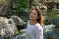 Latina woman smiling standing in the shade with glowing hair in a stream with waterfalls in the background