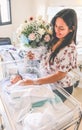 Young woman with her newborn baby in a hospital, holding a bouquet of flowers Royalty Free Stock Photo