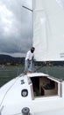 Latino adult man drives a sailboat on the lake with sails unfurled as a physical activity, sport and hobby to relax for the weeken