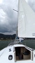 Latino adult man drives a sailboat on the lake with sails unfurled as a physical activity, sport and hobby to relax for the weeken