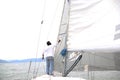 Latino adult man drives a sailboat on the lake with sails unfurled as a physical activity, sport and hobby to relax for the weeken