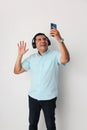 Latino adult man uses technology with his cell phone and headphones to listen to music, play video games, make video calls, watch Royalty Free Stock Photo