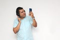 Latino adult man uses technology with his cell phone and headphones to listen to music, play video games, make video calls, watch Royalty Free Stock Photo