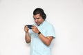 Latino adult man uses technology with his cell phone and headphones to listen to music, play video games, make video calls, watch Royalty Free Stock Photo