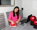 Latino adult woman working at home office in her dining room with laptop, glasses and notebook in the new normal due to the Covid-