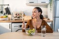 Latino attractive woman wear apron eat green salad in kitchen at home. Young beautiful girl feeling happy and enjoy eating Royalty Free Stock Photo