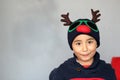 Latino boy 7 years old with Christmas hat with reindeer ears and sweater. Christmas decoration Royalty Free Stock Photo