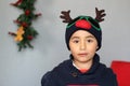 Latino boy 7 years old with Christmas hat with reindeer ears and sweater. Christmas decoration Royalty Free Stock Photo