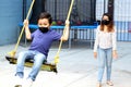 Latino family, mom and 6-year-old boy with face masks playing swing, new normal by covid-19 Royalty Free Stock Photo