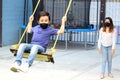 Latino family, mom and 6-year-old boy with face masks playing swing, new normal by covid-19 Royalty Free Stock Photo