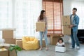 Latino father with beard, Asian mother and little cute daughter carrying packed cardboard boxes into their new home with happiness