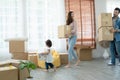 Latino father with beard, Asian mother and little cute daughter carrying packed cardboard boxes into their new home with happiness