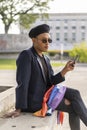 Latino gay male with makeup on wearing trendy hat holding cell phone Royalty Free Stock Photo