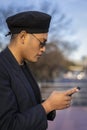 Latino gay male with makeup on wearing trendy hat looking at cell phone Royalty Free Stock Photo