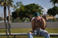 Latino and Hispanic boy, young, rebellious, with headscarf, looking at camera thoughtful, sad, lonely, sitting on a bench.