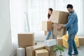 Latino man with beard and Asian woman couple help to carry packed cardboard boxes into their new home where they were moving in