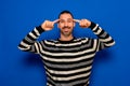 Latino man with beard wearing striped sweater smiling pointing to the head with the finger of both hands, great idea or