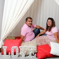 Latino man and woman couple in love and happy share their love with kisses and hugs under a teepee and the sign that says `love` c