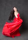 Latino Woman with long hair in red waving dress dancing in action with flying fabric