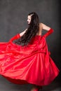 Latino Woman with long hair in red waving dress dancing in action with flying fabric