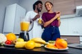 Latino woman and man working at juice bar and cutting fruits, making fresh smoothies from bananas,orange and melon. she