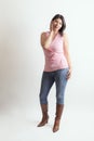 Latino woman with a pink t-shirt and cowboy boots posing in studio with a cute pose Royalty Free Stock Photo