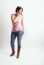 Latino woman with a pink t-shirt and cowboy boots posing in studio with a cute pose Royalty Free Stock Photo