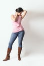 Latino woman with a pink t-shirt and cowboy boots posing in studio with a cute pose Royalty Free Stock Photo