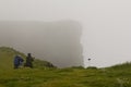 Latrabjarg bird cliffs in West Fjords, Iceland. Foggy misty morning with tourists photographing puffins.