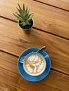 Latte art cappuccino and cactus plant on a wood table Royalty Free Stock Photo