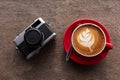 Latte art coffee and film camera on wooden table