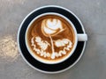 Latte art coffee Flower shape in black and white cup on the cement background Royalty Free Stock Photo