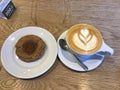 latte art coffee with heart and flower draw by milk on top in white cup and a brown sugar donut Royalty Free Stock Photo