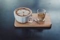 Latte art coffee on the white cup of hot coffee on wooden tray and dark table. Royalty Free Stock Photo