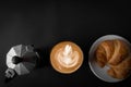 Latte art coffee in a white cup Two sides with Italian Moka pots, coffee and croissants, top view, black background, empty space, Royalty Free Stock Photo