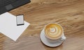 Latte Art coffee in white cup on wooden surface table. Black smartphone blank screen and white sheet on table. Copy space and work Royalty Free Stock Photo