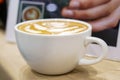 Latte art coffee in white rose and white ceramic coffee cup on wooden table in cafe Royalty Free Stock Photo