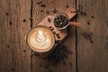 Latte art on hot latte coffee. Aroma coffee cup and coffee beans on wooden desk Royalty Free Stock Photo