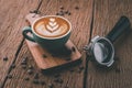 Latte art on hot latte coffee. Aroma coffee cup and coffee beans on wooden desk Royalty Free Stock Photo