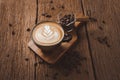 Latte art on hot latte coffee. Aroma coffee cup and coffee beans on wooden desk Royalty Free Stock Photo