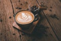 Latte art on hot latte coffee. Aroma coffee cup and coffee beans on wooden desk Royalty Free Stock Photo