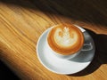 Latte or Cappuccino art coffee cup top view on wood table with sunlight in cafe Royalty Free Stock Photo