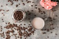 Latte in a ceramic cup, jar with coffee beans and roses on the table. Top view Royalty Free Stock Photo